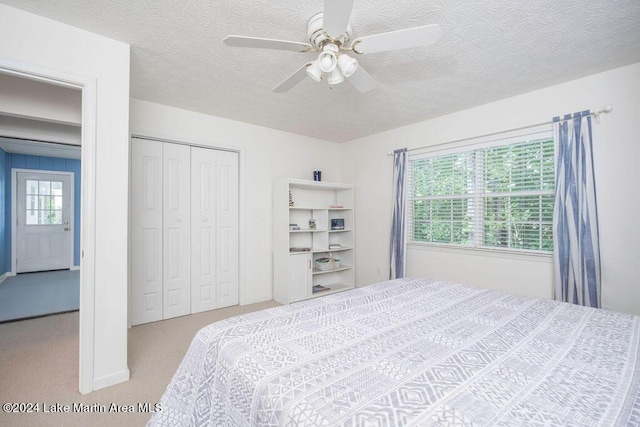 bedroom with light carpet, a textured ceiling, a closet, and ceiling fan