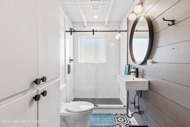 full bath with a stall shower, beam ceiling, a sink, and toilet