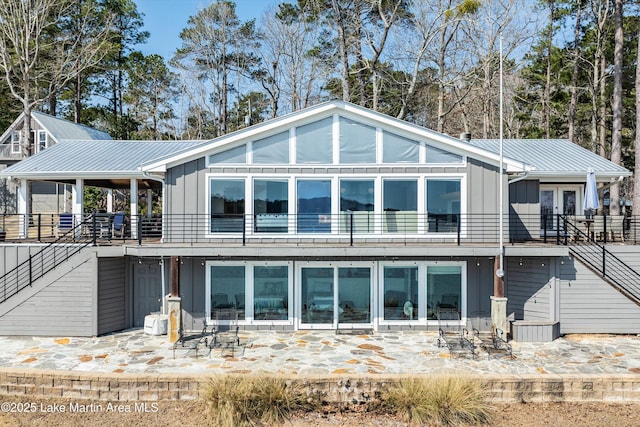 rear view of property featuring stairs, metal roof, french doors, and board and batten siding