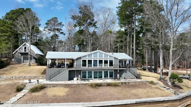 view of front of home with stairs, metal roof, and a wooden deck