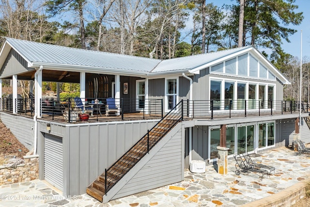 rear view of property featuring stairway, metal roof, an attached garage, a patio area, and board and batten siding