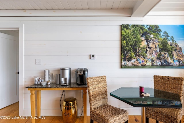 interior space featuring beam ceiling, wooden walls, and wood finished floors