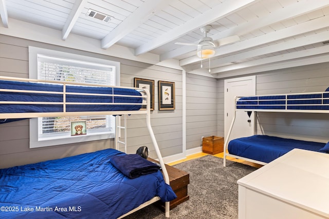 bedroom featuring wood walls, visible vents, and beamed ceiling