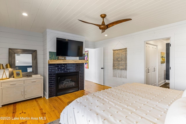 bedroom featuring wooden ceiling, light wood-style flooring, and a brick fireplace