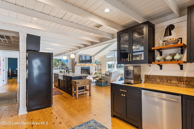 kitchen with dishwasher, lofted ceiling with beams, open floor plan, freestanding refrigerator, and a fireplace