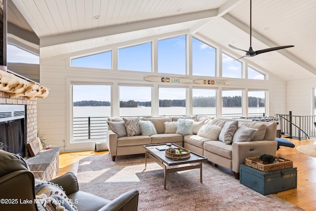 living area featuring a wealth of natural light, a water view, light wood-style flooring, and a brick fireplace