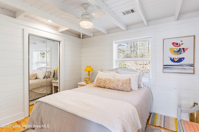 bedroom with wooden ceiling, wood walls, visible vents, light wood-type flooring, and beam ceiling