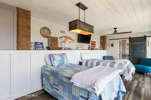 bedroom with wood ceiling, a barn door, visible vents, and dark wood-style flooring