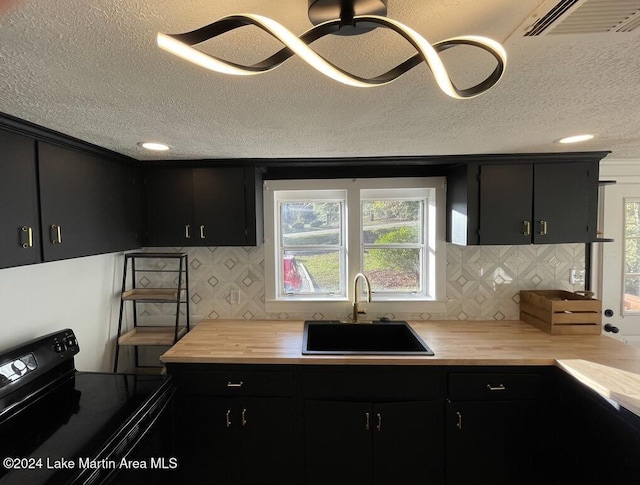 kitchen with electric range, butcher block countertops, sink, and tasteful backsplash