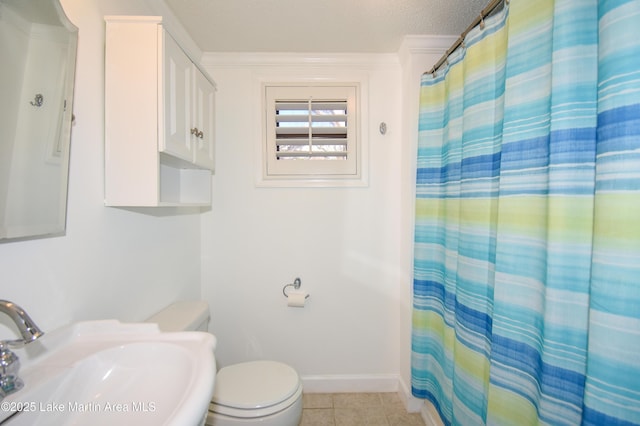 full bath featuring a textured ceiling, toilet, a sink, baseboards, and tile patterned floors