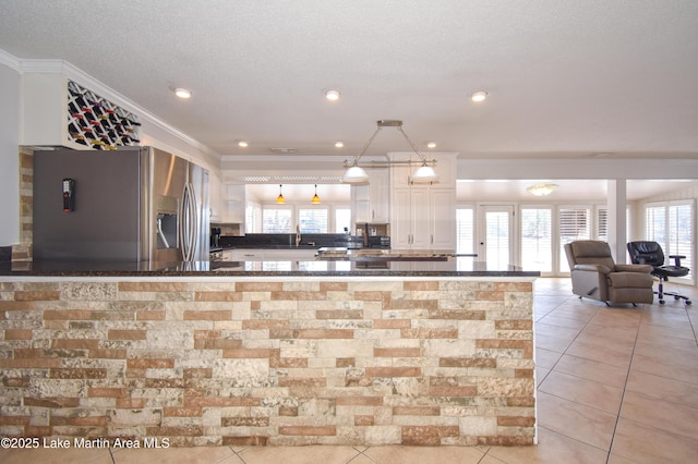 kitchen featuring dark countertops, stainless steel refrigerator with ice dispenser, white cabinets, and crown molding