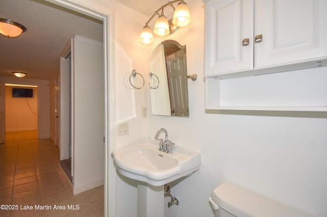 bathroom with a textured ceiling, toilet, and tile patterned floors