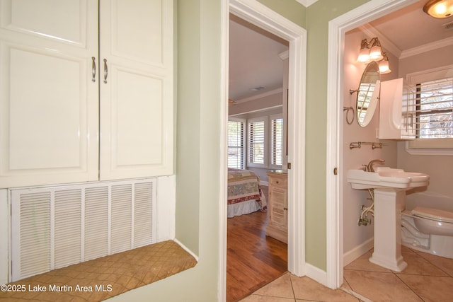 bathroom with baseboards, ornamental molding, toilet, and tile patterned floors