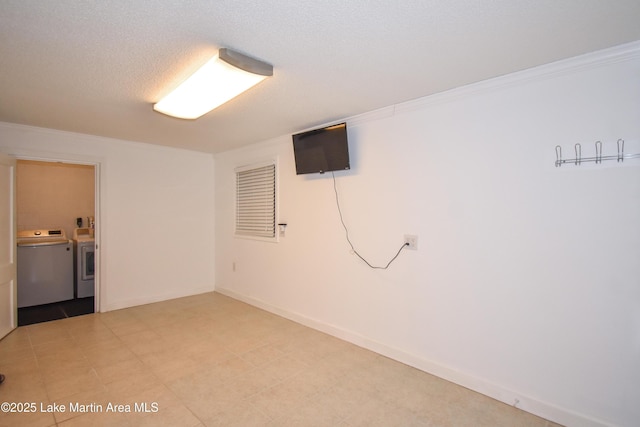 finished below grade area featuring a textured ceiling, independent washer and dryer, baseboards, and crown molding