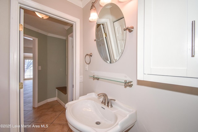 bathroom featuring crown molding, baseboards, a sink, and tile patterned floors