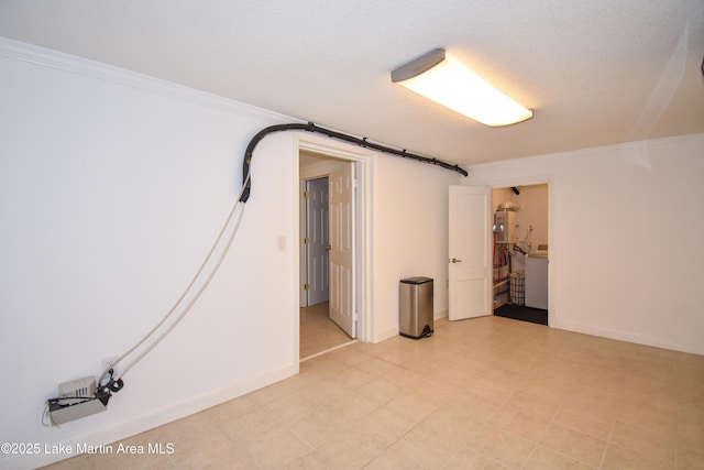 finished below grade area featuring washer / clothes dryer, water heater, ornamental molding, a textured ceiling, and baseboards