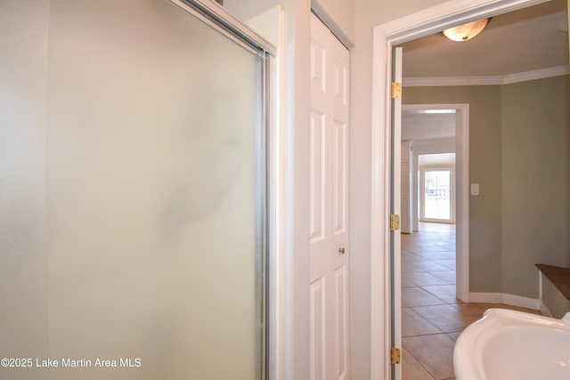 bathroom featuring ornamental molding, tile patterned flooring, a shower with door, and baseboards