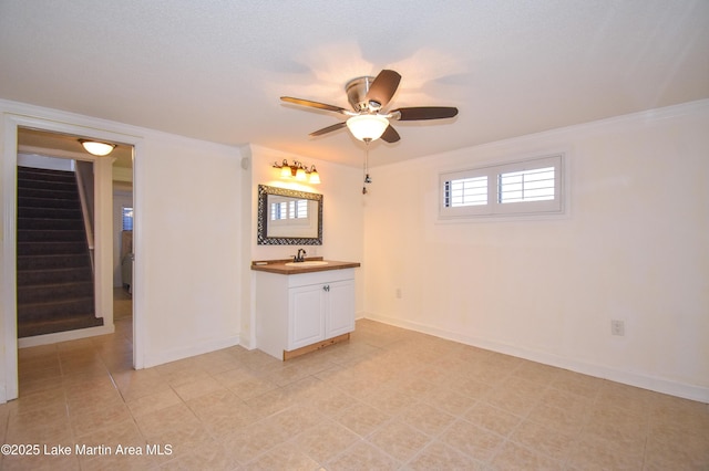 unfurnished room with ornamental molding, a sink, stairway, and baseboards