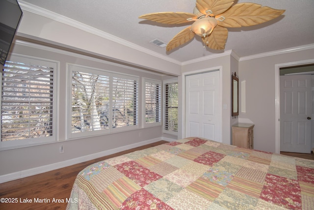 bedroom with a textured ceiling, wood finished floors, visible vents, baseboards, and ornamental molding