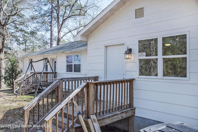 property entrance with a shingled roof and a deck