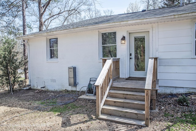 doorway to property with a shingled roof, brick siding, and crawl space