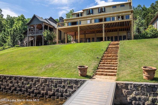 back of property with a lawn and a water view