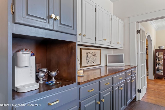 kitchen with white cabinetry, dark hardwood / wood-style floors, butcher block countertops, and crown molding