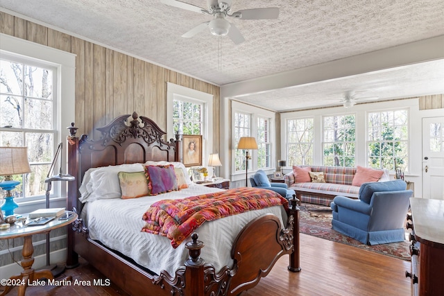 bedroom with ceiling fan, ornamental molding, hardwood / wood-style floors, and a textured ceiling