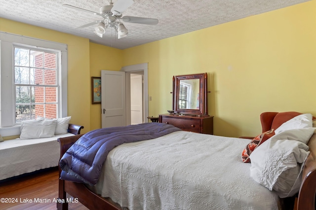 bedroom featuring ceiling fan, wood-type flooring, and a textured ceiling