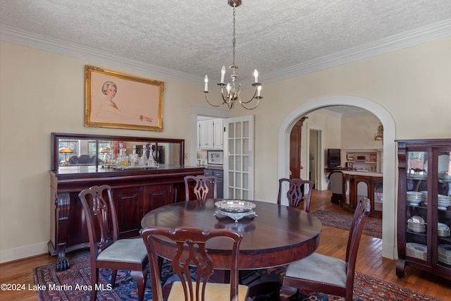 dining room featuring an inviting chandelier, hardwood / wood-style floors, ornamental molding, and a textured ceiling