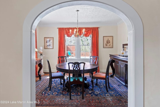 dining area featuring a notable chandelier, wood-type flooring, ornamental molding, and a textured ceiling