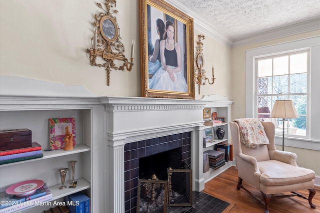 sitting room with crown molding, wood-type flooring, a fireplace, and a textured ceiling