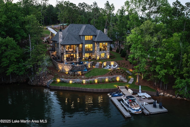 back of house with a lawn, a balcony, and a water view