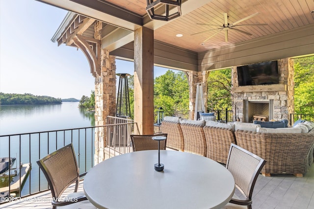 view of patio / terrace with an outdoor living space with a fireplace, ceiling fan, and a water view