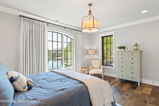 bedroom featuring a water view, crown molding, and dark wood-type flooring