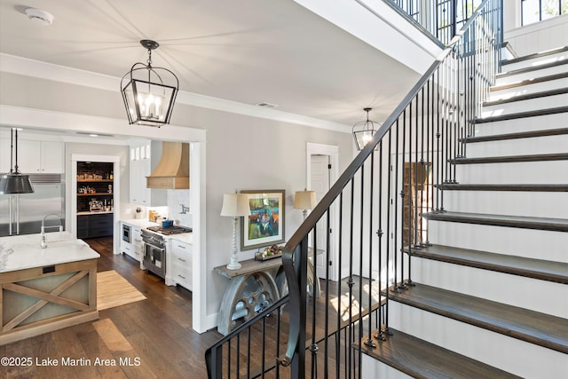 stairs featuring hardwood / wood-style floors, an inviting chandelier, and crown molding