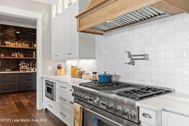 kitchen with high end range, white cabinets, and custom exhaust hood