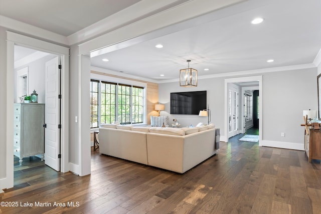 living room featuring ornamental molding, dark wood-type flooring, and a notable chandelier