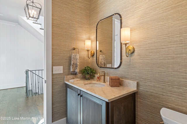 bathroom featuring an inviting chandelier, vanity, hardwood / wood-style floors, and toilet