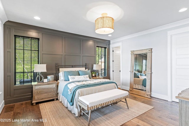 bedroom with hardwood / wood-style flooring, multiple windows, and crown molding