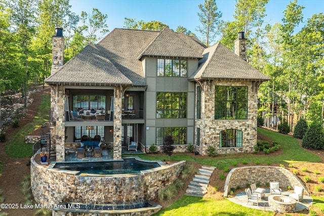 back of house featuring a patio area, a balcony, and an outdoor fire pit