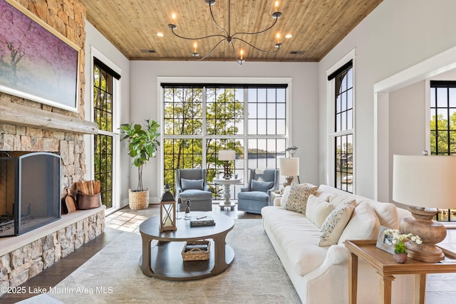 living room with wood-type flooring, wooden ceiling, a fireplace, and a chandelier