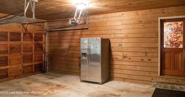 garage featuring wooden walls, wooden ceiling, stainless steel refrigerator with ice dispenser, and a garage door opener