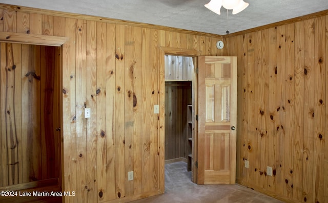 interior space featuring carpet flooring, ornamental molding, a textured ceiling, and wooden walls