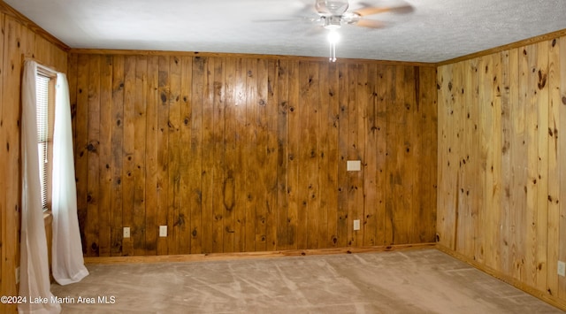 carpeted empty room featuring a textured ceiling, crown molding, and wood walls