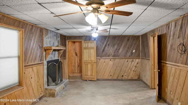 interior space featuring wood walls, a fireplace, and ceiling fan