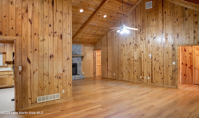 additional living space featuring wood ceiling, wooden walls, beamed ceiling, light hardwood / wood-style floors, and a stone fireplace