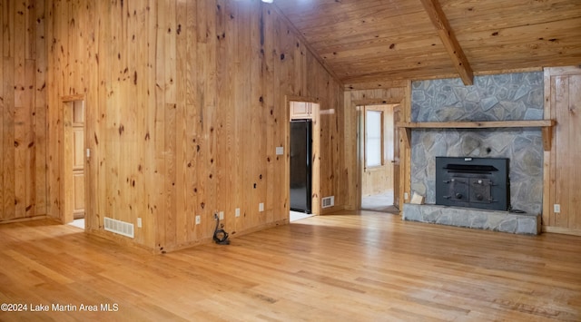 unfurnished living room with beam ceiling, a stone fireplace, hardwood / wood-style floors, and wood ceiling