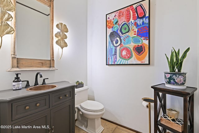half bath with toilet, vanity, and baseboards