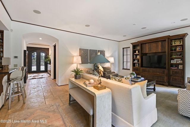 living area with stone tile flooring, arched walkways, french doors, and recessed lighting